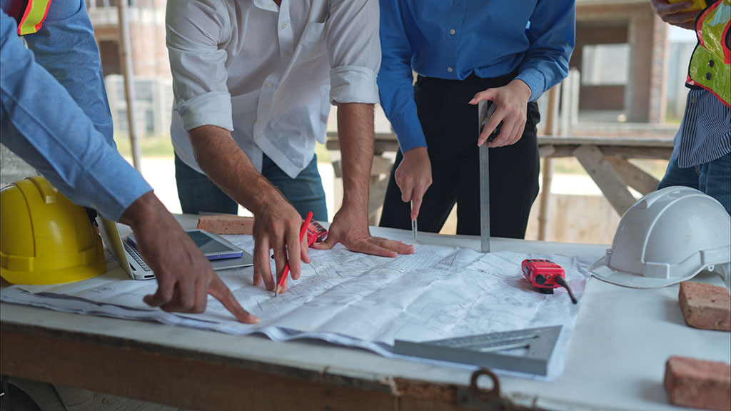 Group of architects and engineers work together to assess the residential home construction site's progress